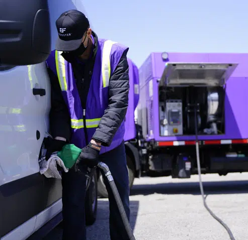 man fueling a white passeneger van